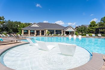 A large outdoor swimming pool with a hot tub in the middle.